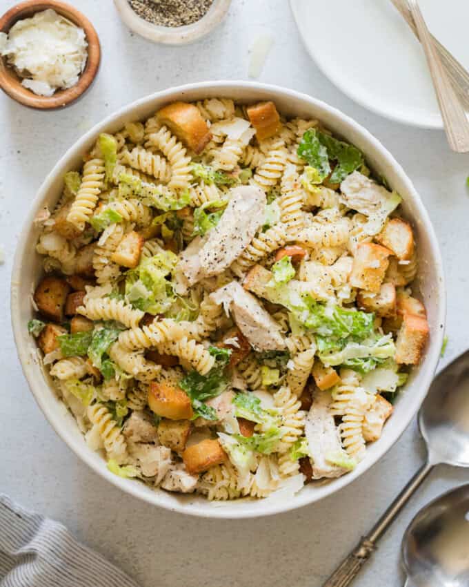 An overhead image of a bowl of chicken caesar pasta salad.