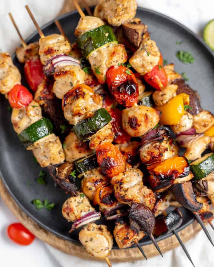 A close up image of grilled chicken kabobs on a plate.