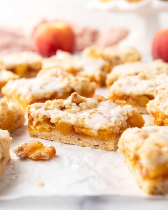 An image of peach crumb bars on white parchment paper.