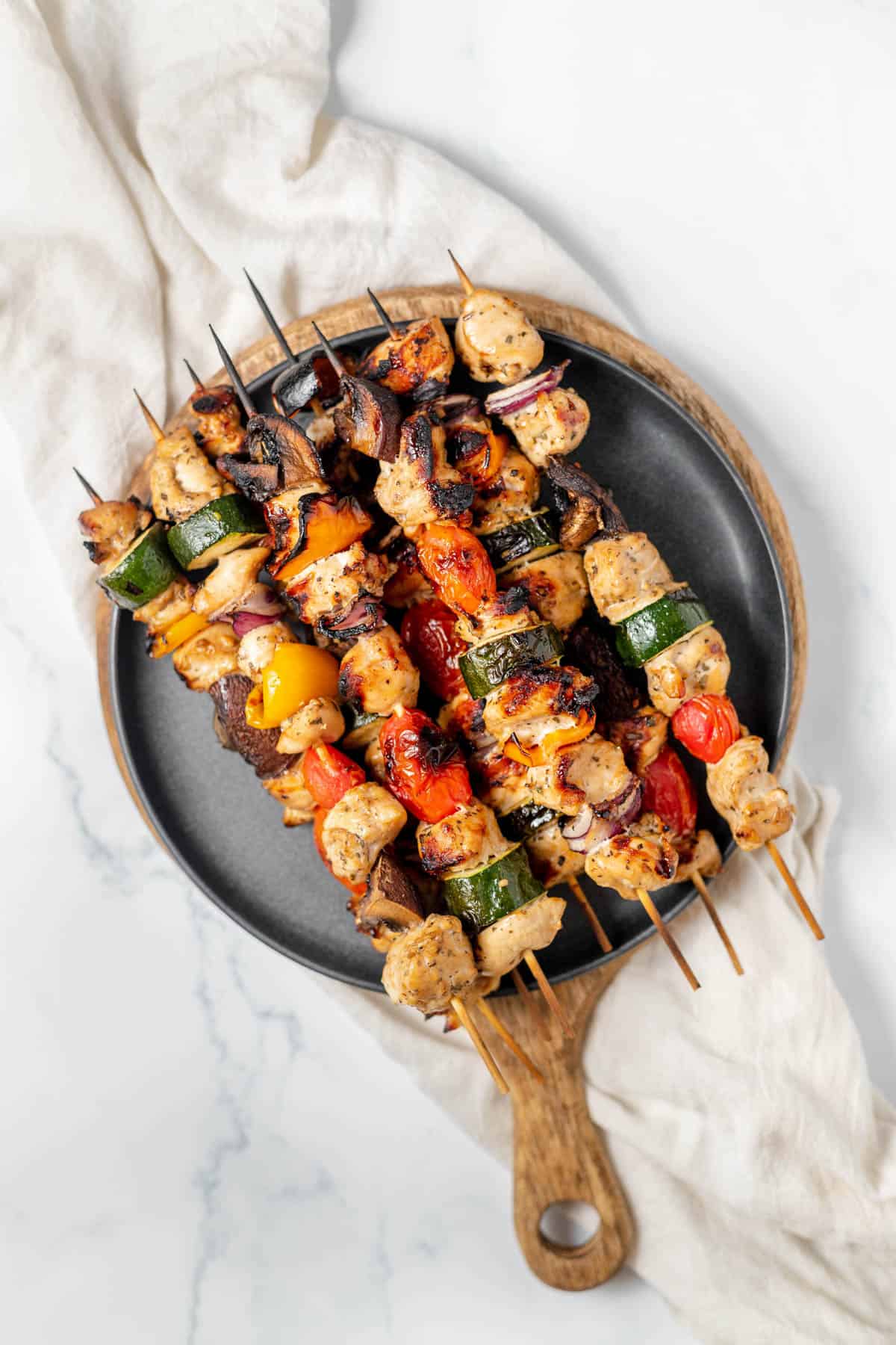 An overhead image of a plate of grilled chicken kabobs.