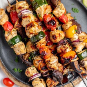 A close up image of grilled chicken kabobs on a plate.