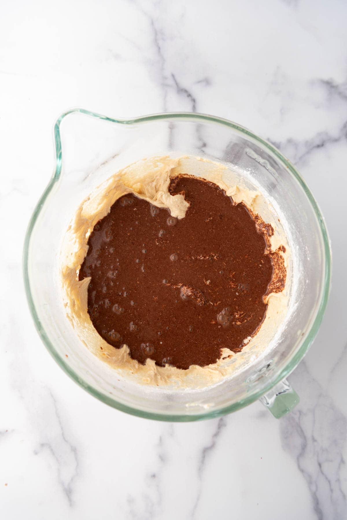 Adding melted chocolate, cocoa powder, and hot water to cake batter.