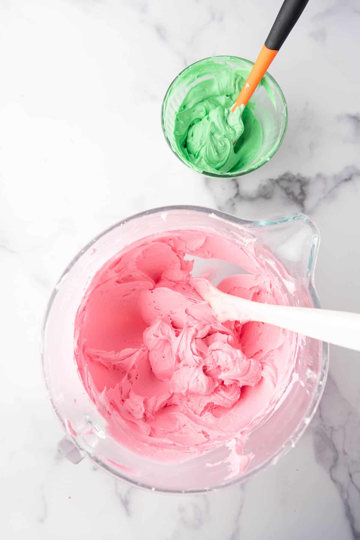 Dying bowls of buttercream frosting  pink and green.