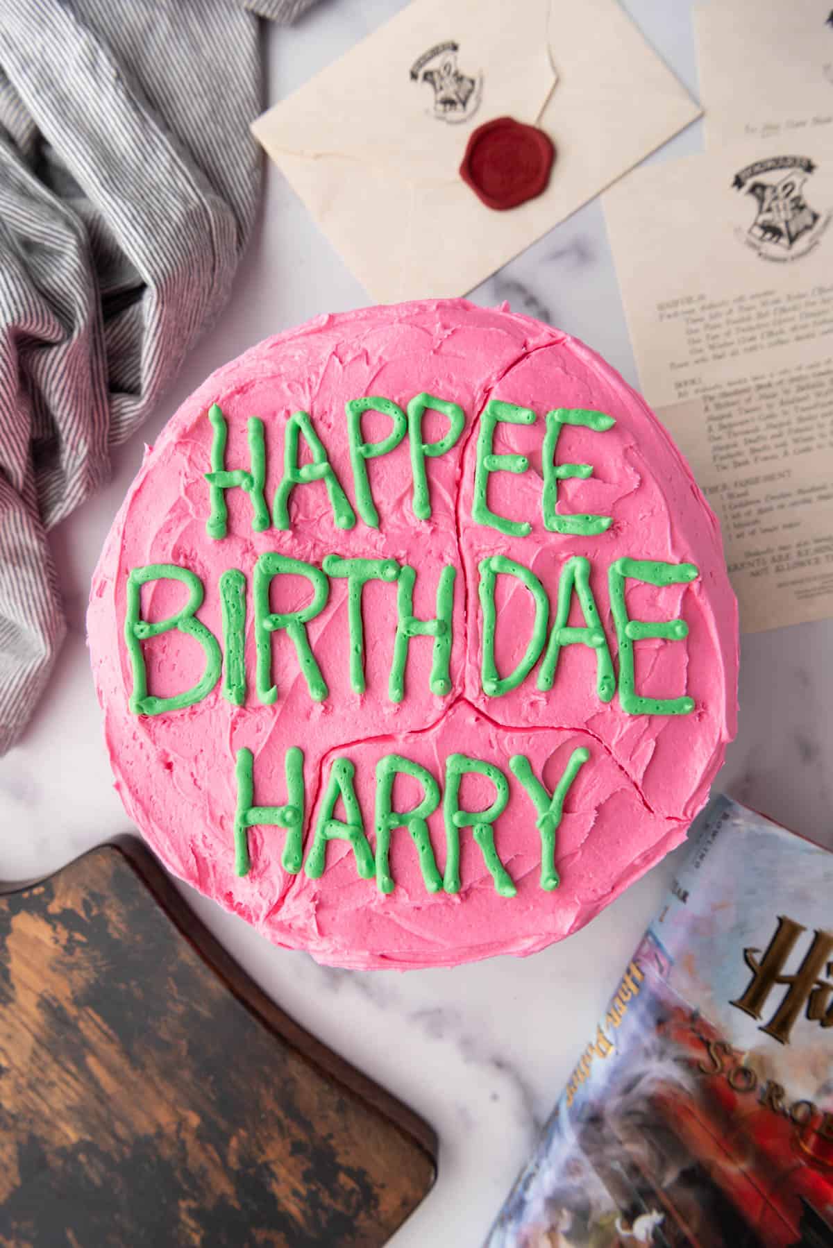 An overhead image of a Harry Potter birthday cake with pink and green frosting.