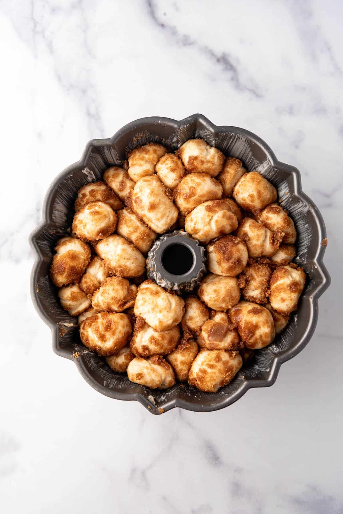 Monkey bread in a bundt pan that has risen, is puffy, and ready to be baked.