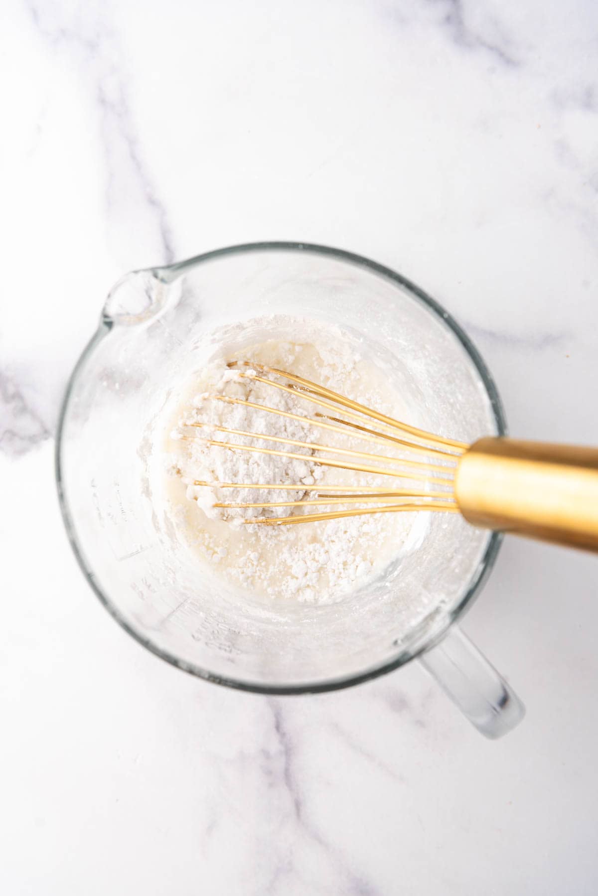 Making a simple vanilla glaze with a whisk in a mixing bowl.