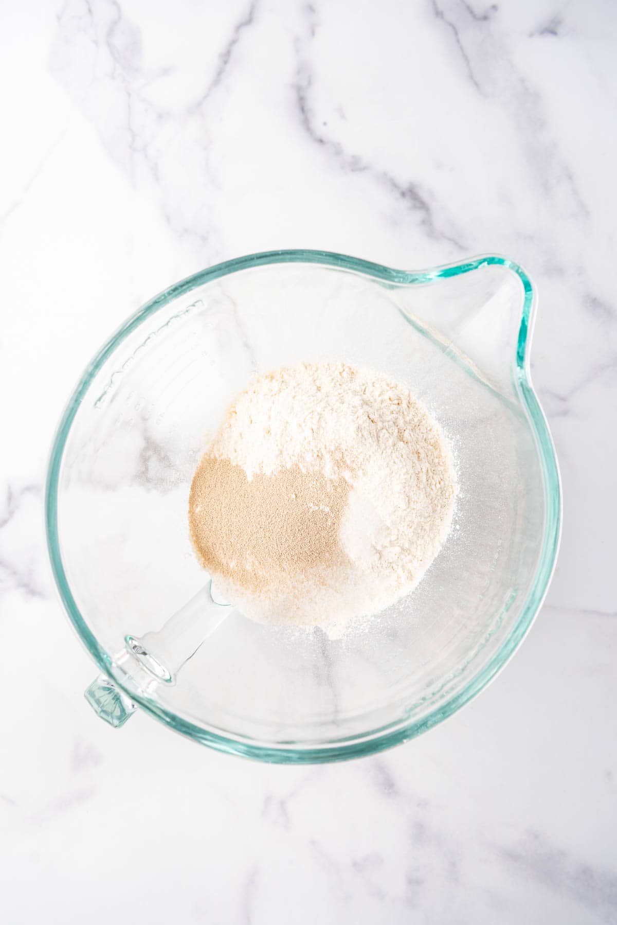 Combining flour and instant yeast in a mixing bowl.