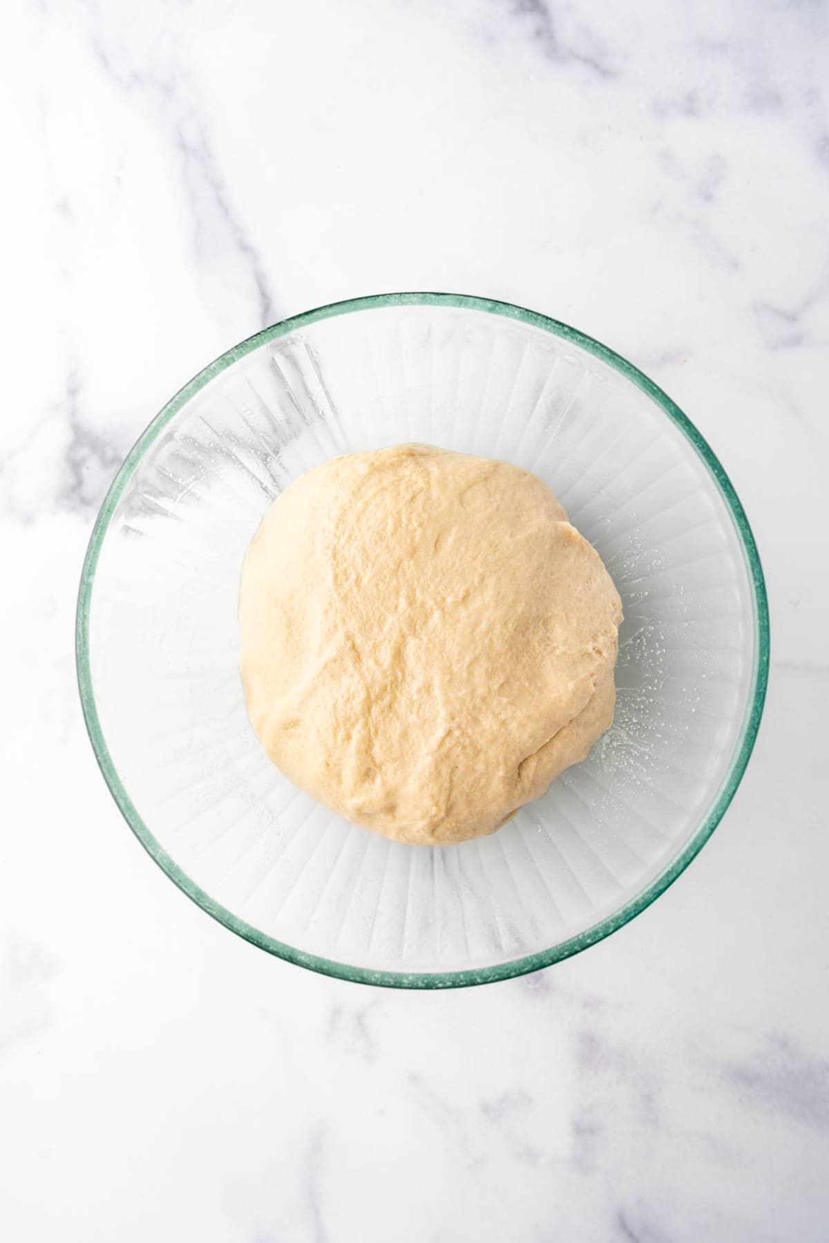 Kneaded monkey bread dough ready to rise in a glass bowl.