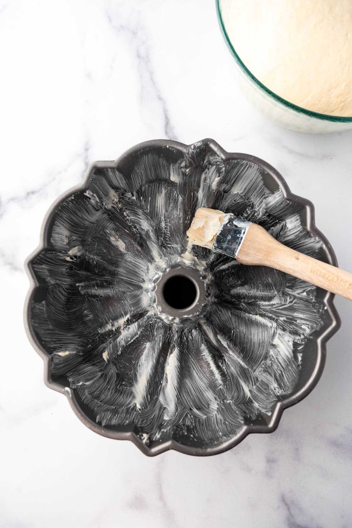 Brushing the crevices of a bundt pan with softened butter.