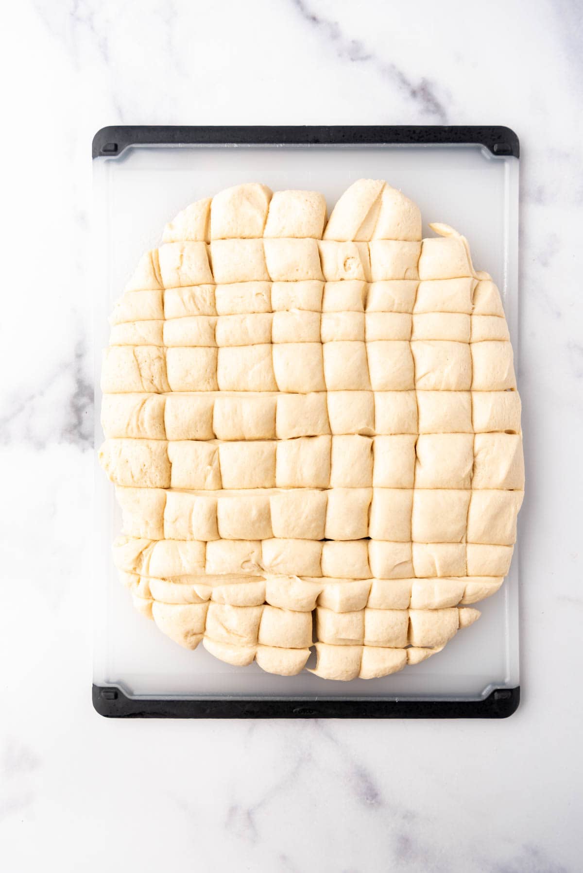 Bread dough that has been cut into small squares on a cutting board.