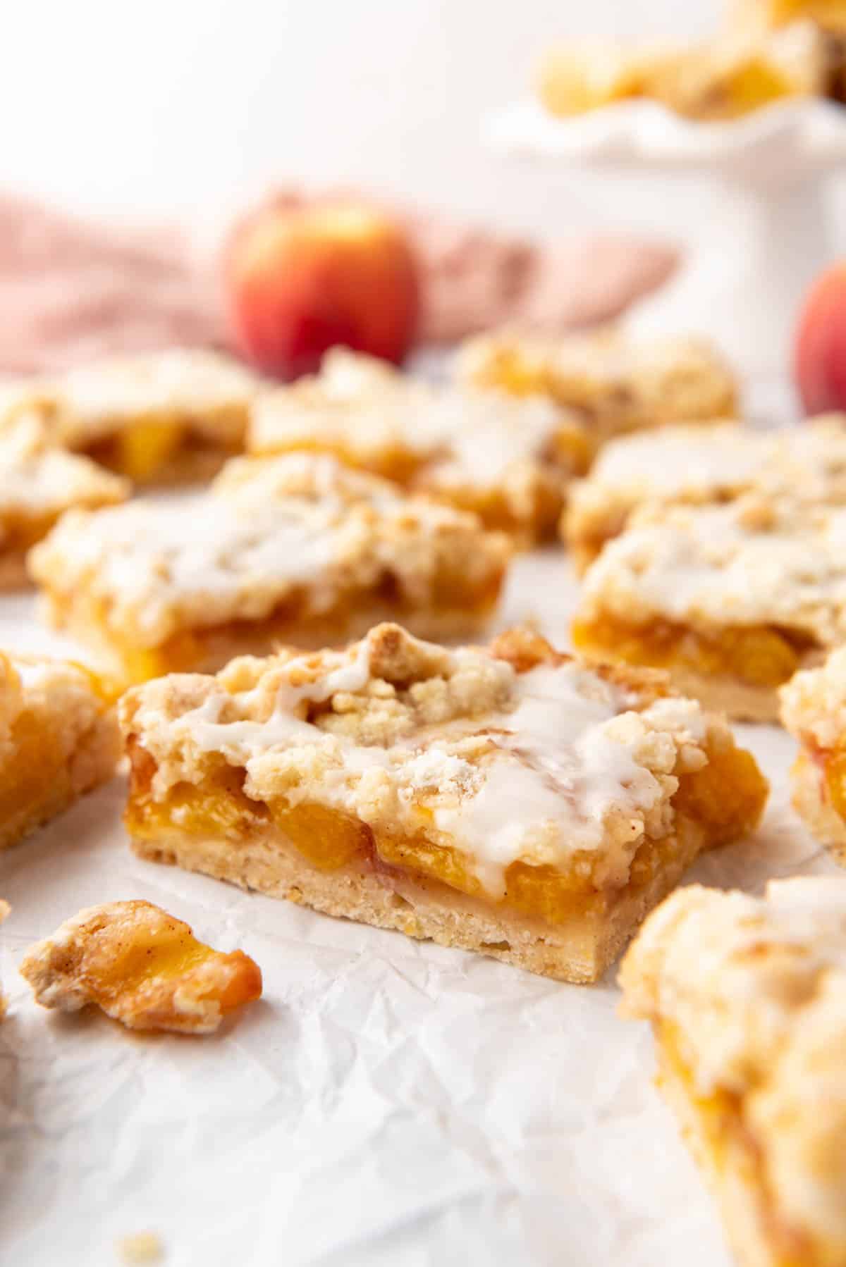 An image of peach crumb bars on white parchment paper.