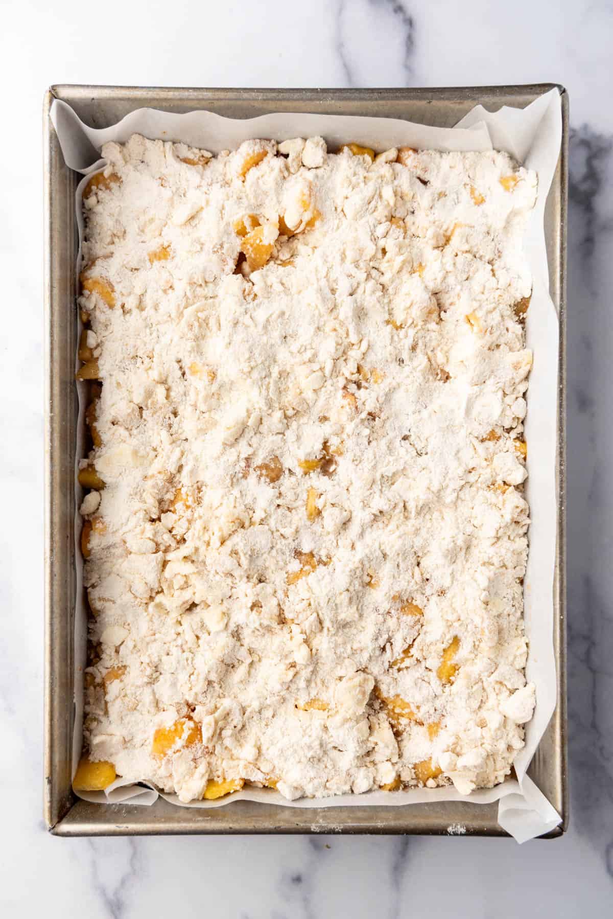 Crumb topping on peach pie bars before baking.