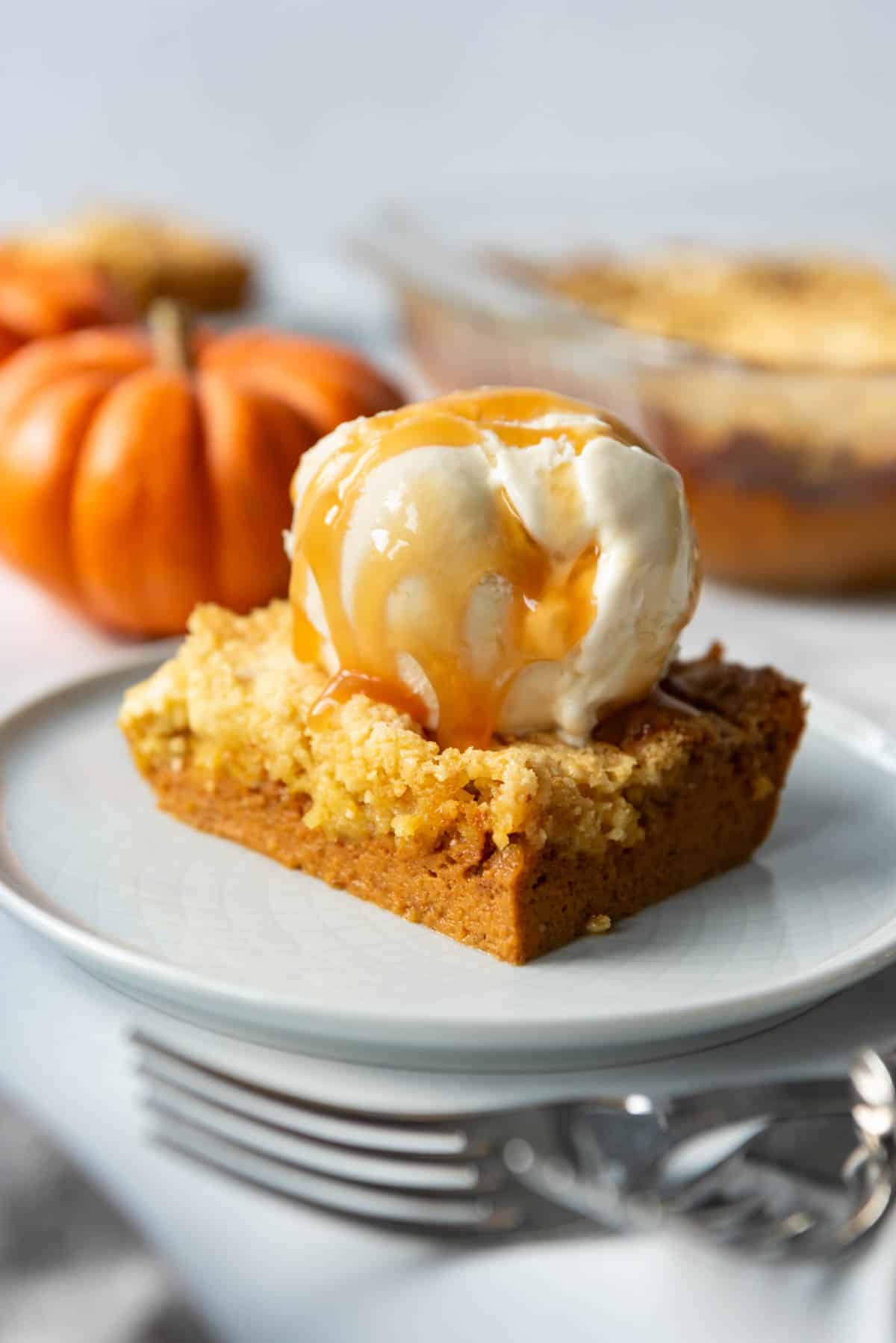 An image of pumpkin dump cake on a plate in front of some forks and mini orange pumpkins.