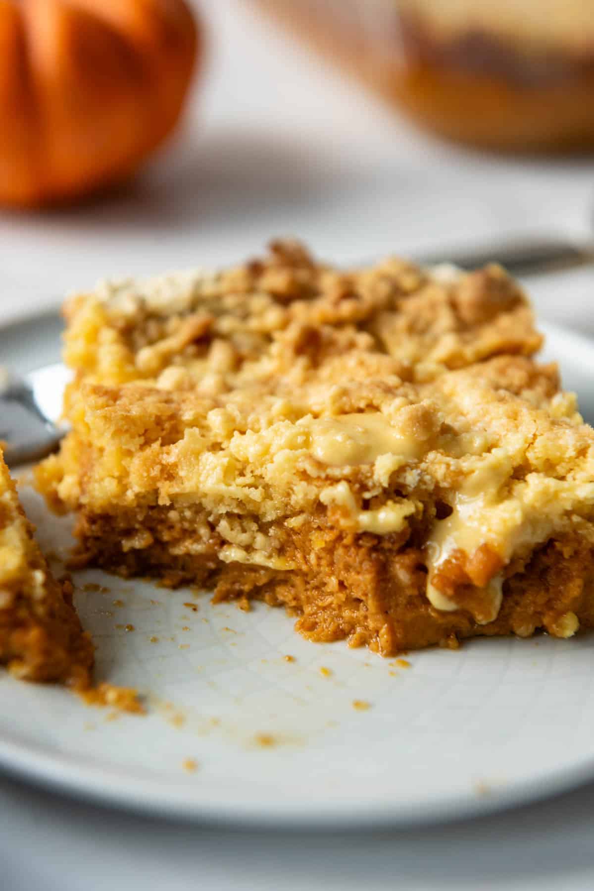 A close up image of a slice of pumpkin dump cake on a plate with a bite taken out of it.