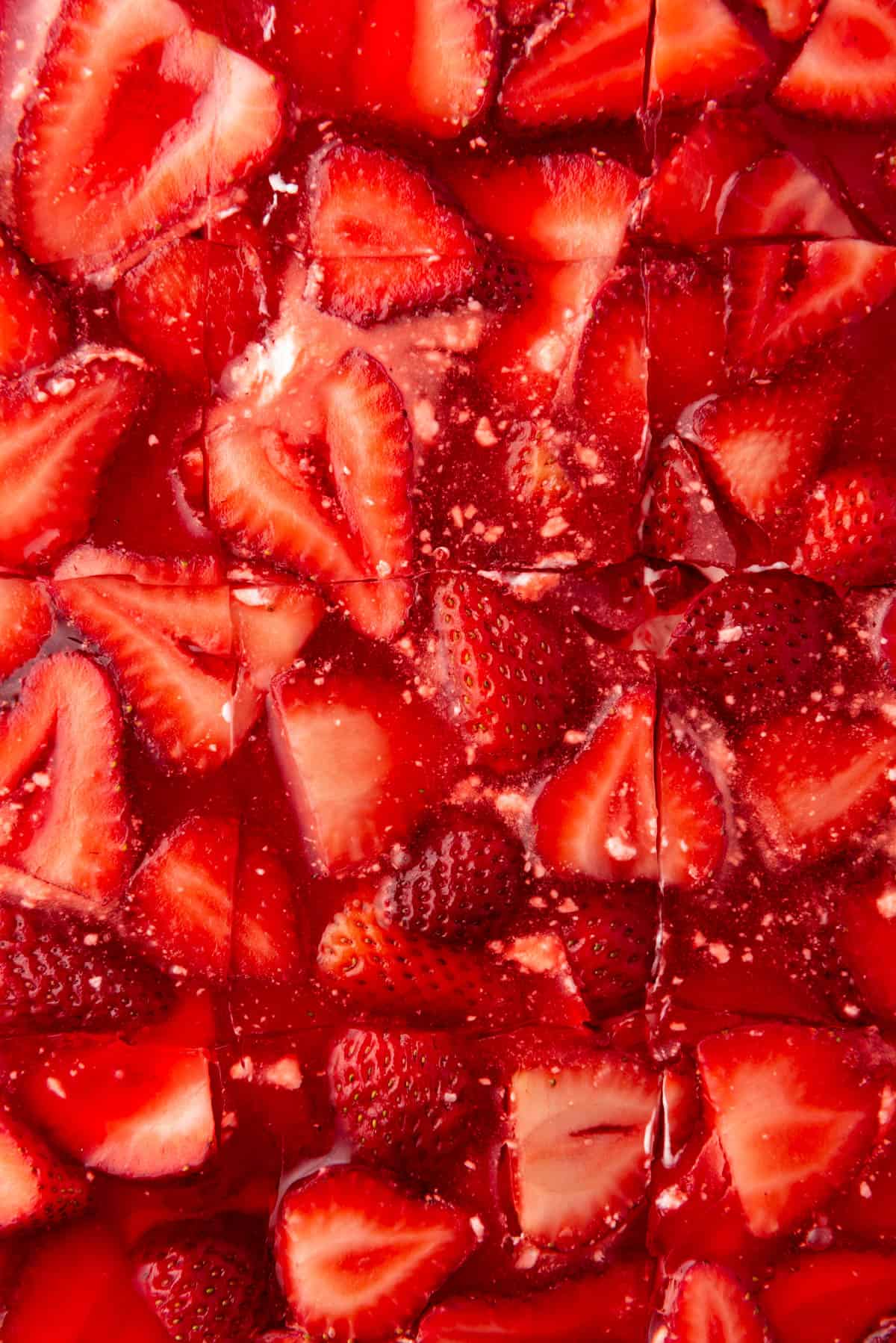 A close up image of sliced strawberries in strawberry jello.