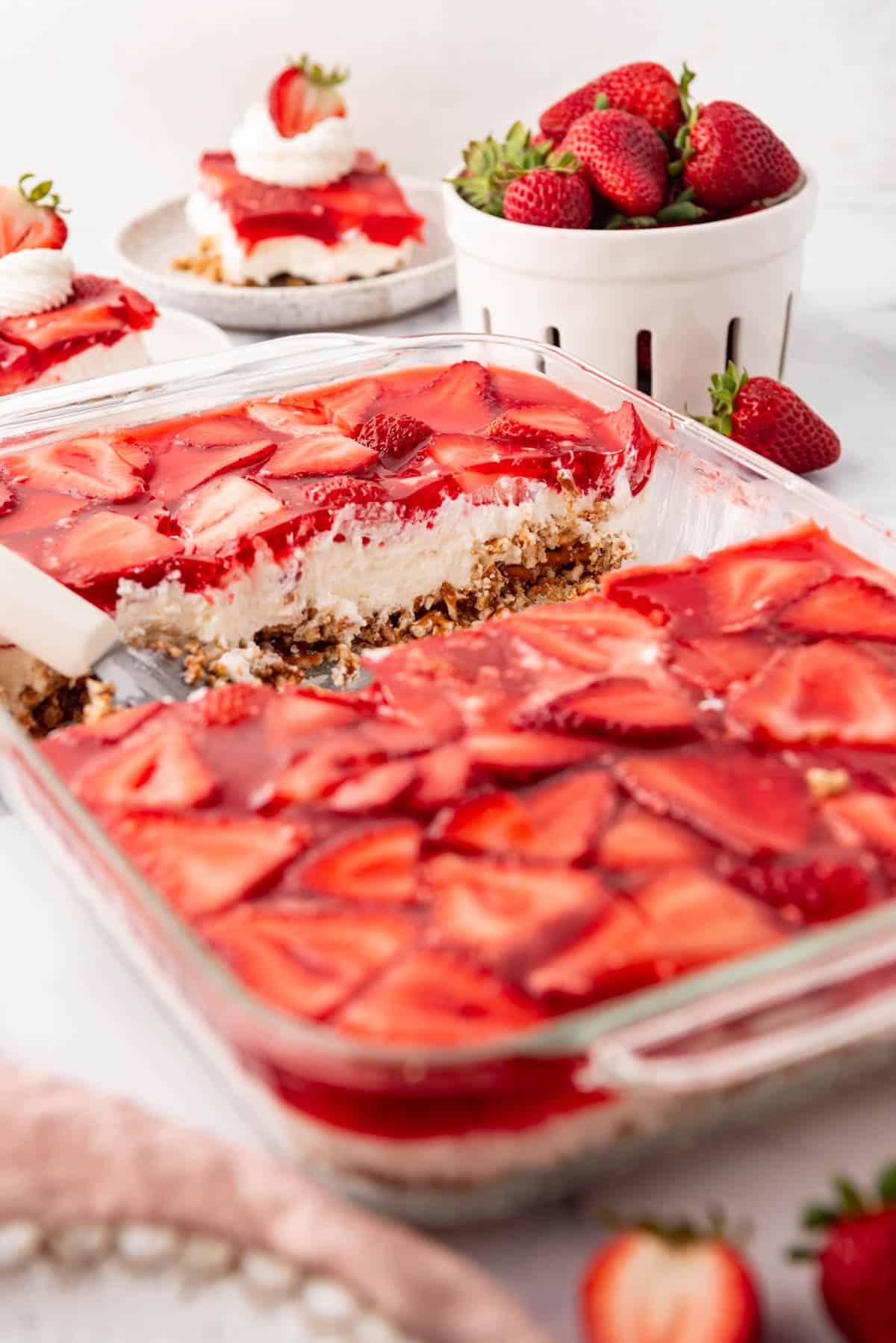 A side angle of a cross-section of strawberry pretzel salad in a baking dish.