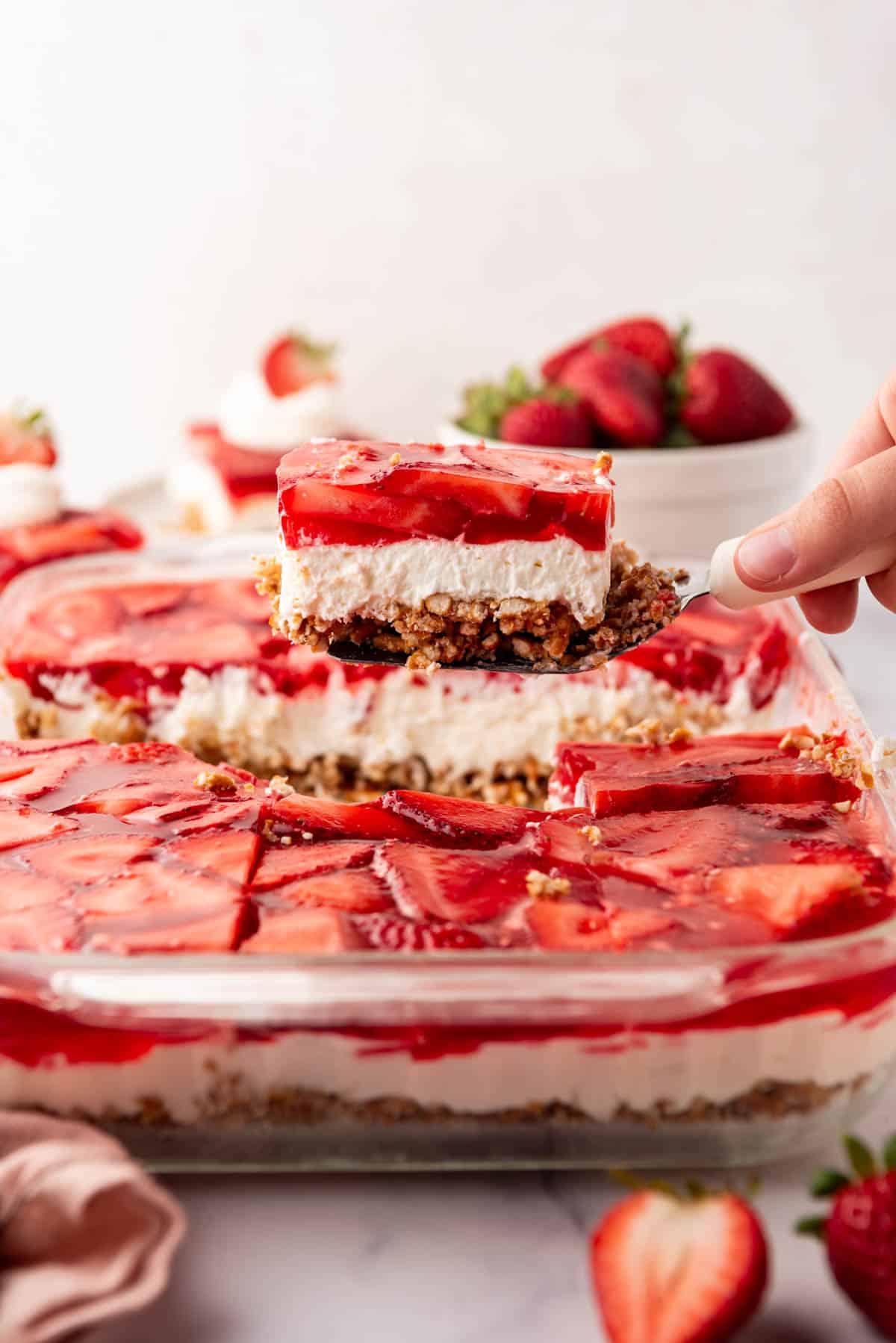 An image of a square of strawberry pretzel salad being lifted up out of the serving dish.