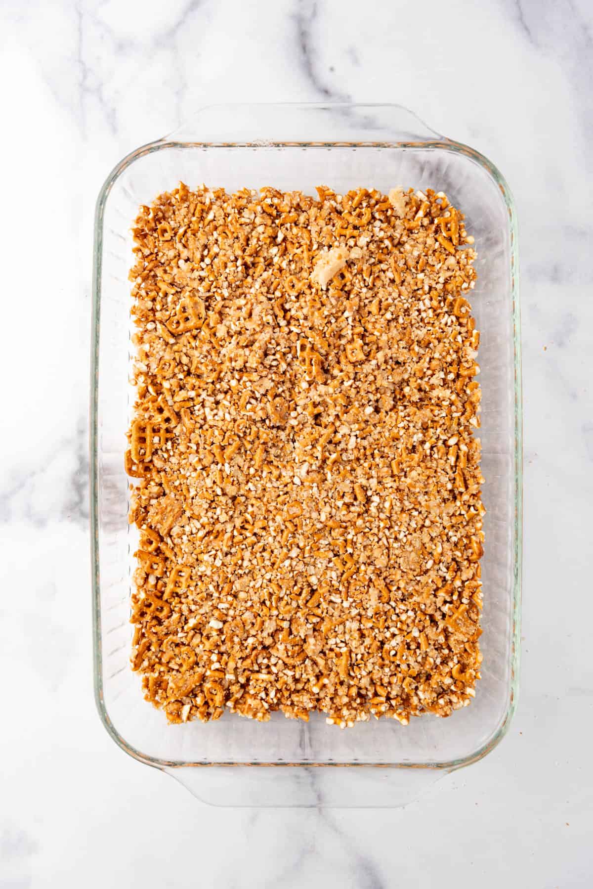 A pretzel crust pressed into the bottom of a 9x13-inch glass baking dish.