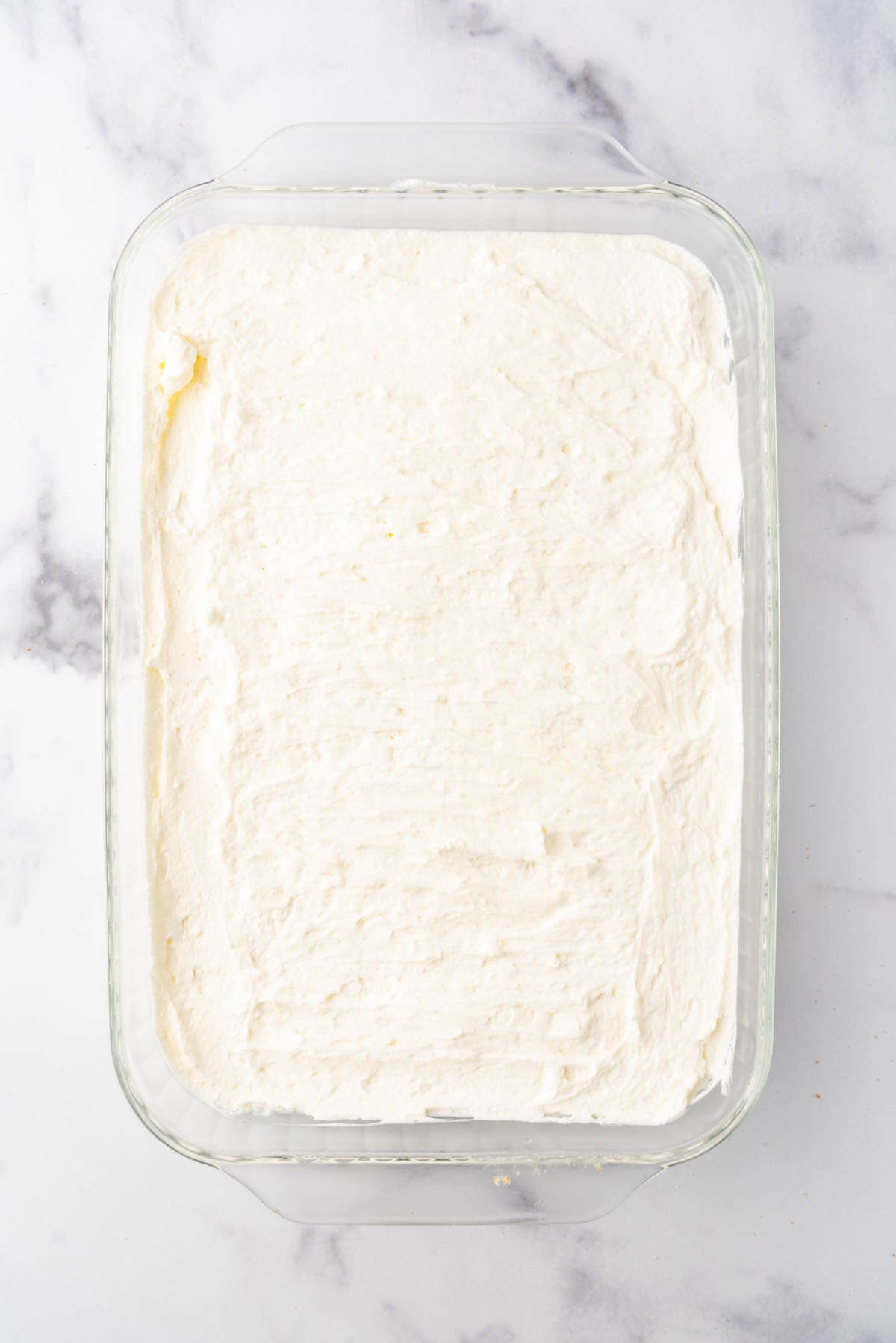 A layer of creamy cream cheese filling in a baking dish.