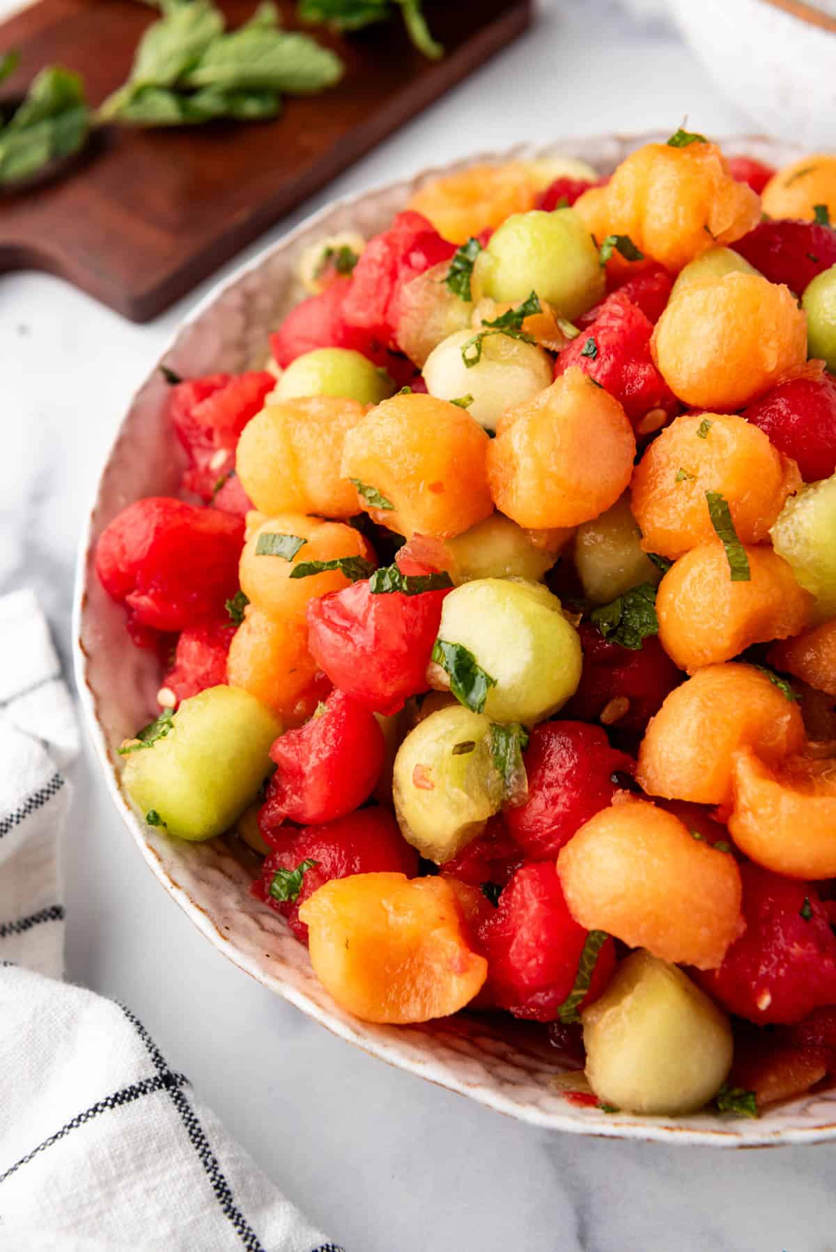 Mixed melon balls in a serving bowl with chopped mint.