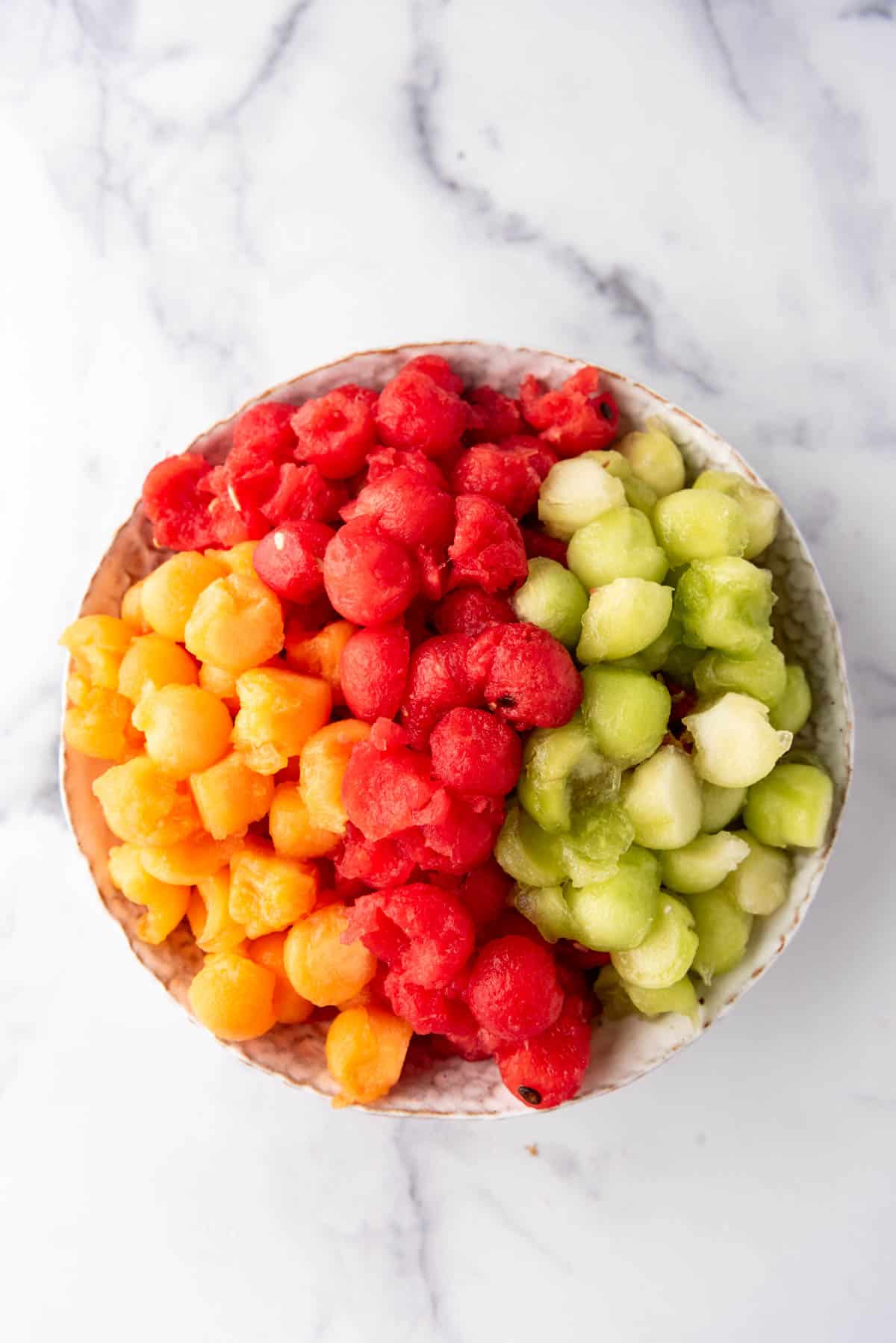 Combining melon balls in a bowl.