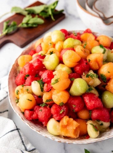 A side view of a large serving bowl of summer melon salad.