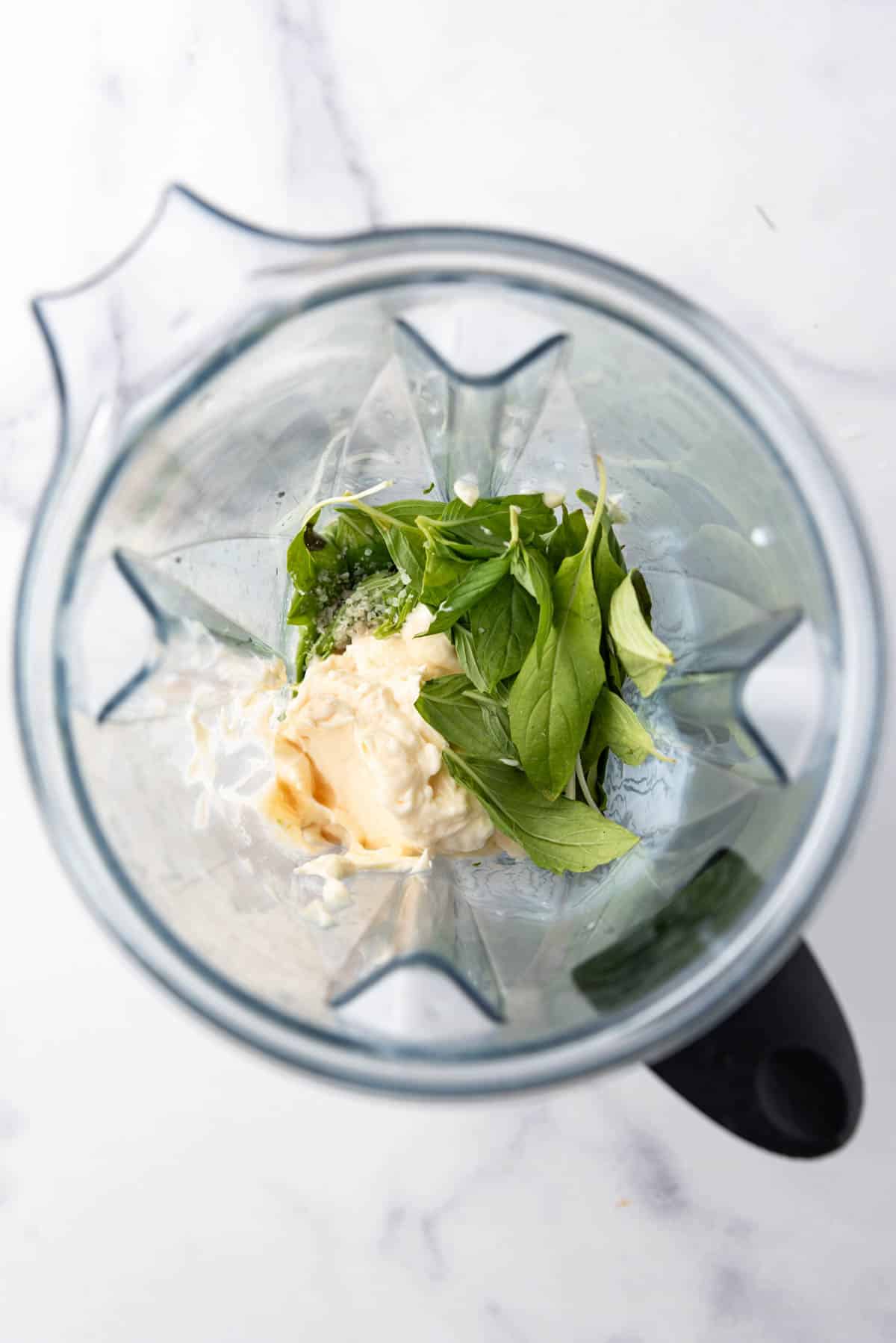 Combining mayo, buttermilk, shallot, and fresh basil in a large blender pitcher.