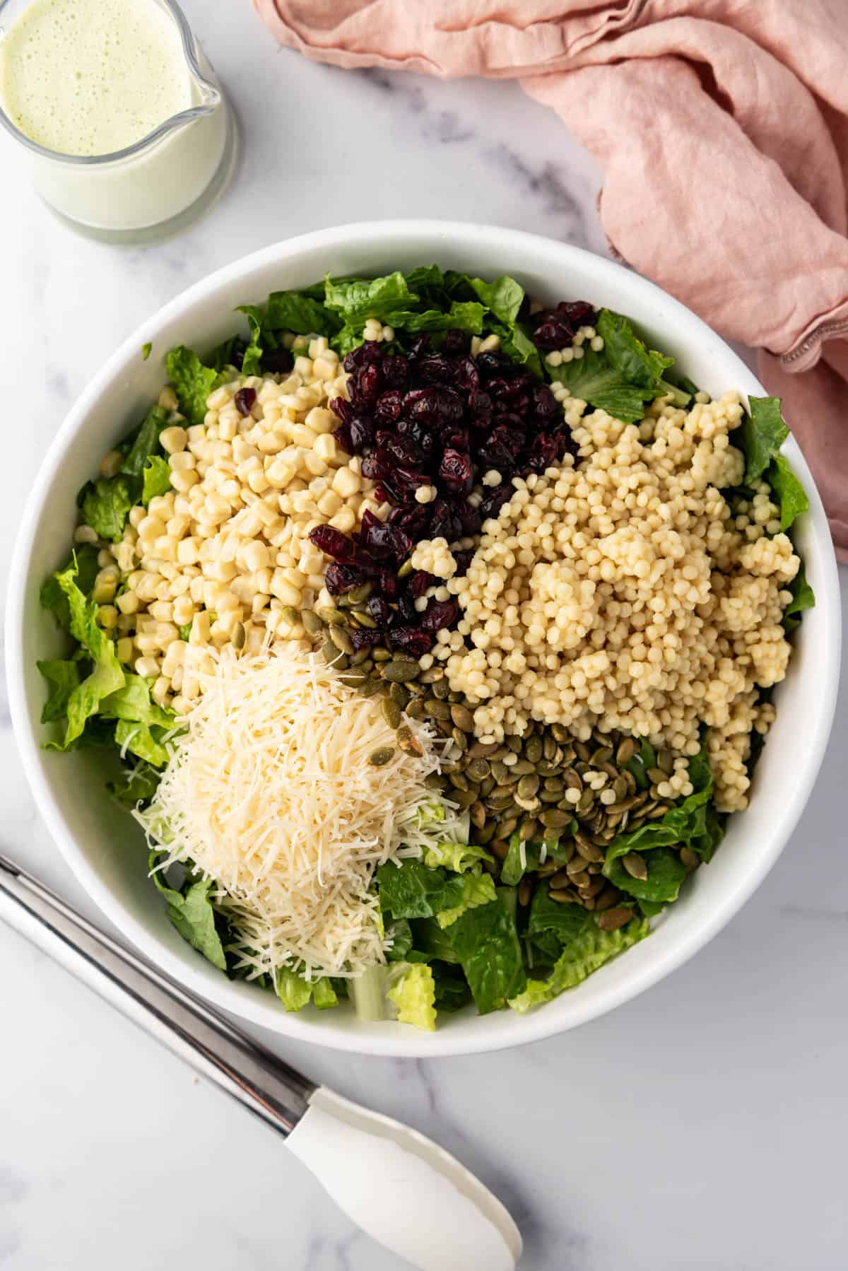 Combining salad ingredients in a large serving bowl with the dressing nearby.