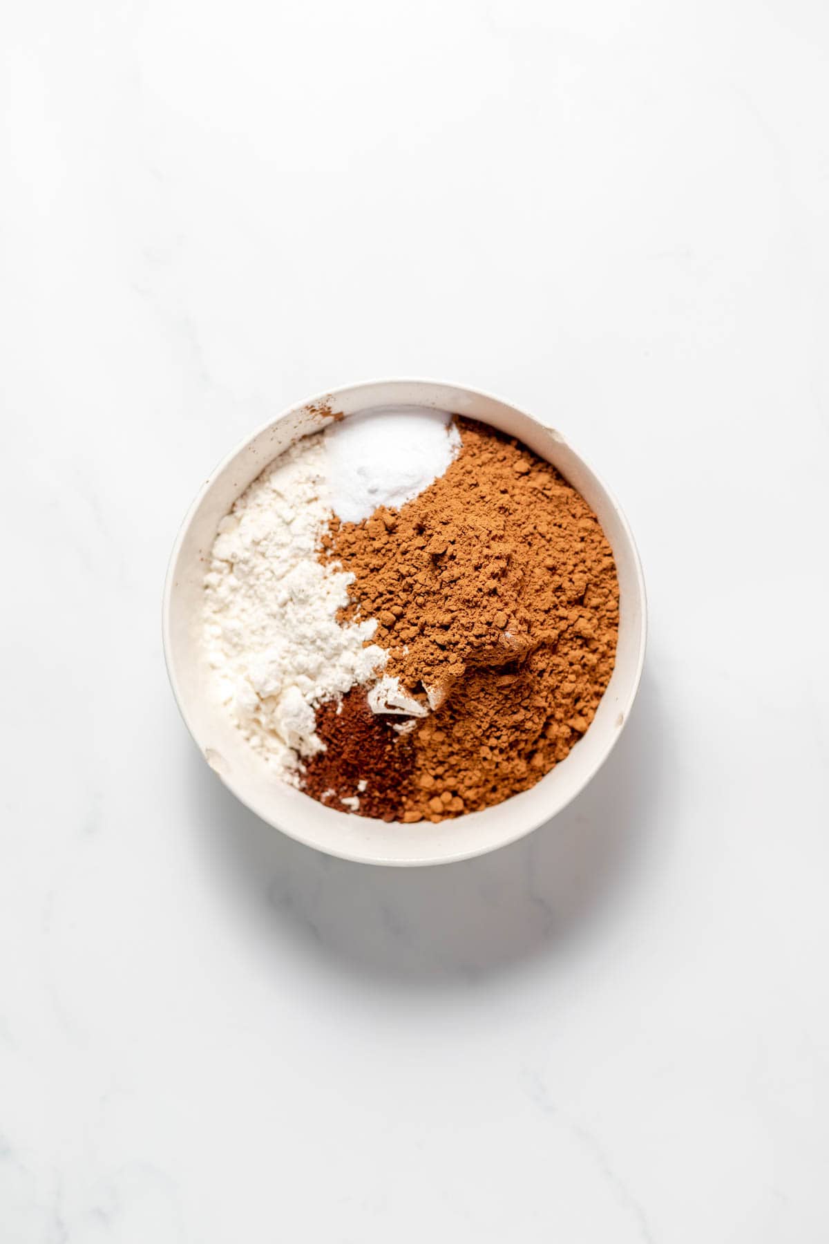 Combining flour and cocoa powder in a bowl.