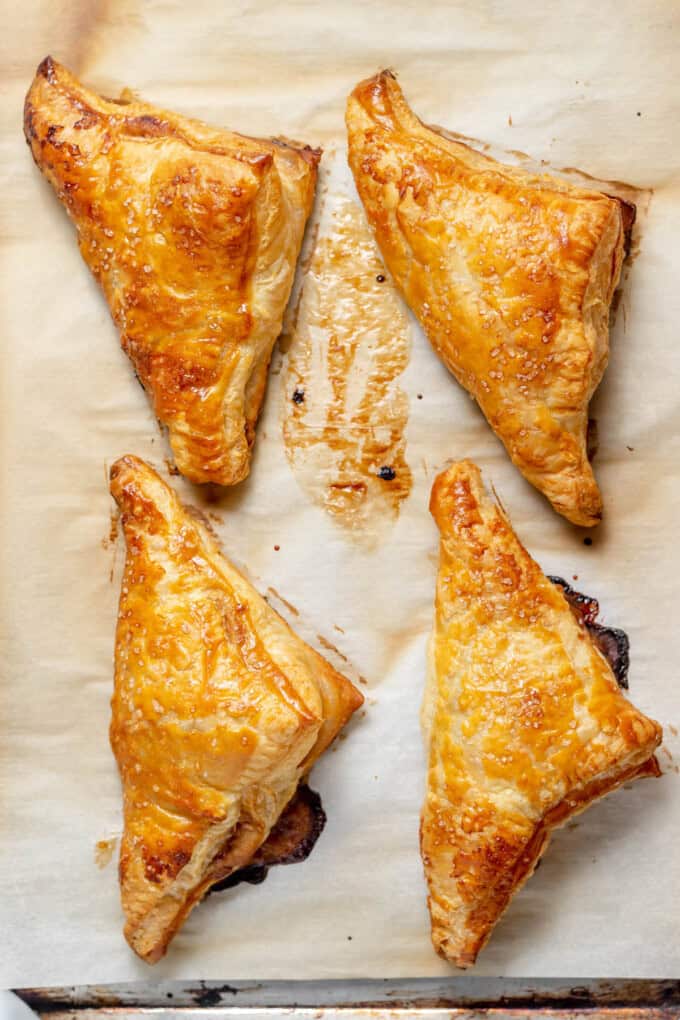 Baked peach turnovers on a baking sheet lined with parchment paper.