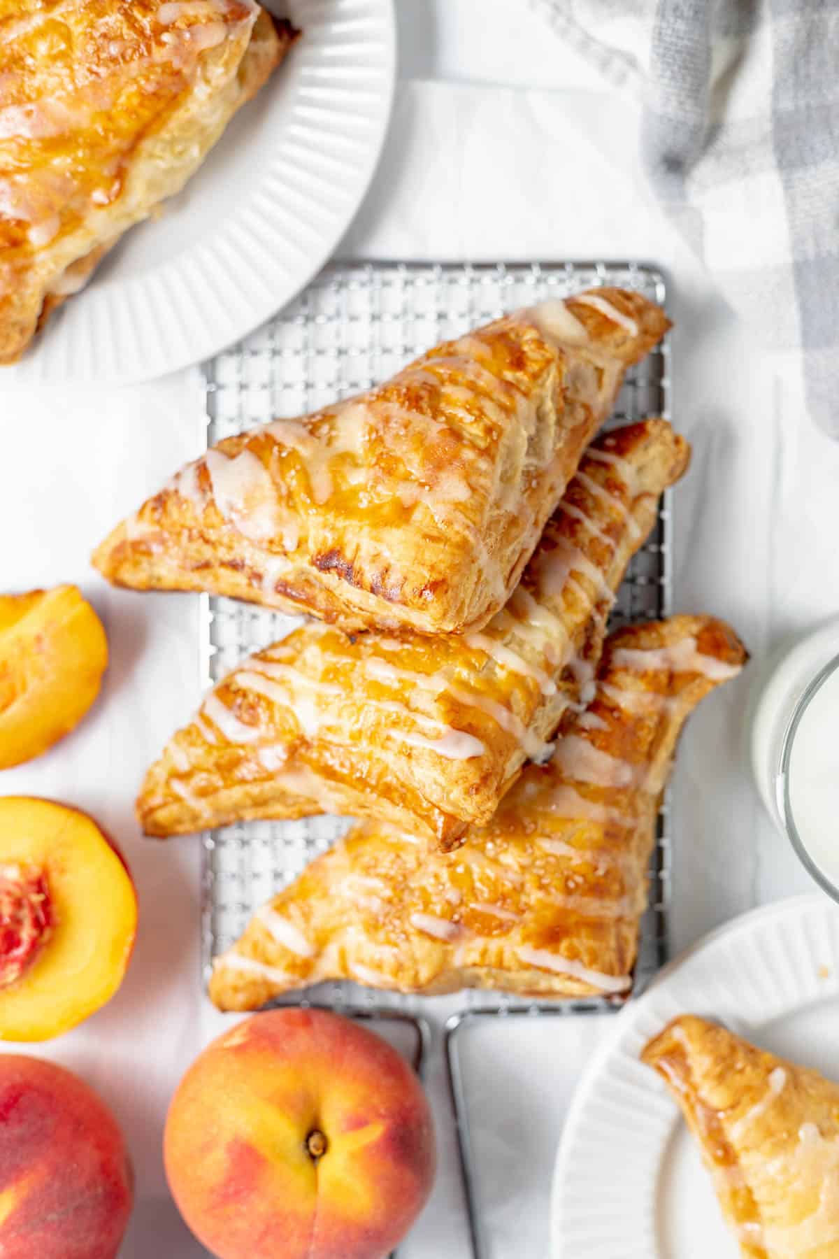 An overhead image of peach turnovers next to fresh peaches.