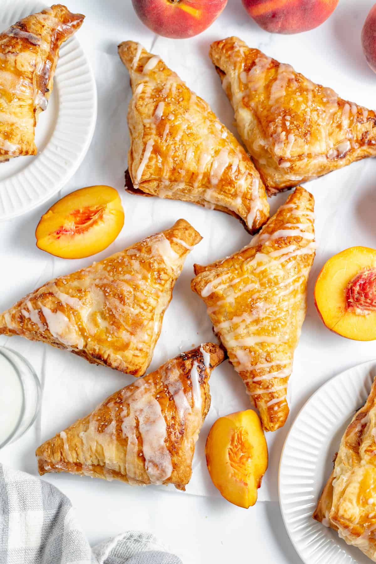 An overhead image of glazed peach turnovers on a white surface.