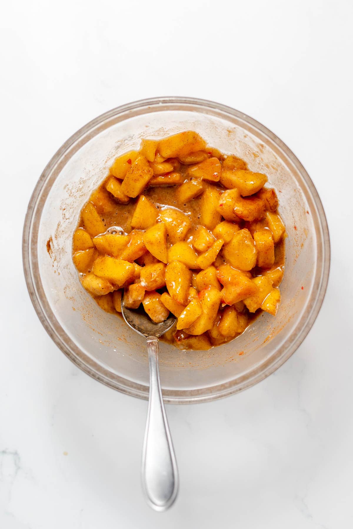 Peach filling in a glass bowl with a spoon.