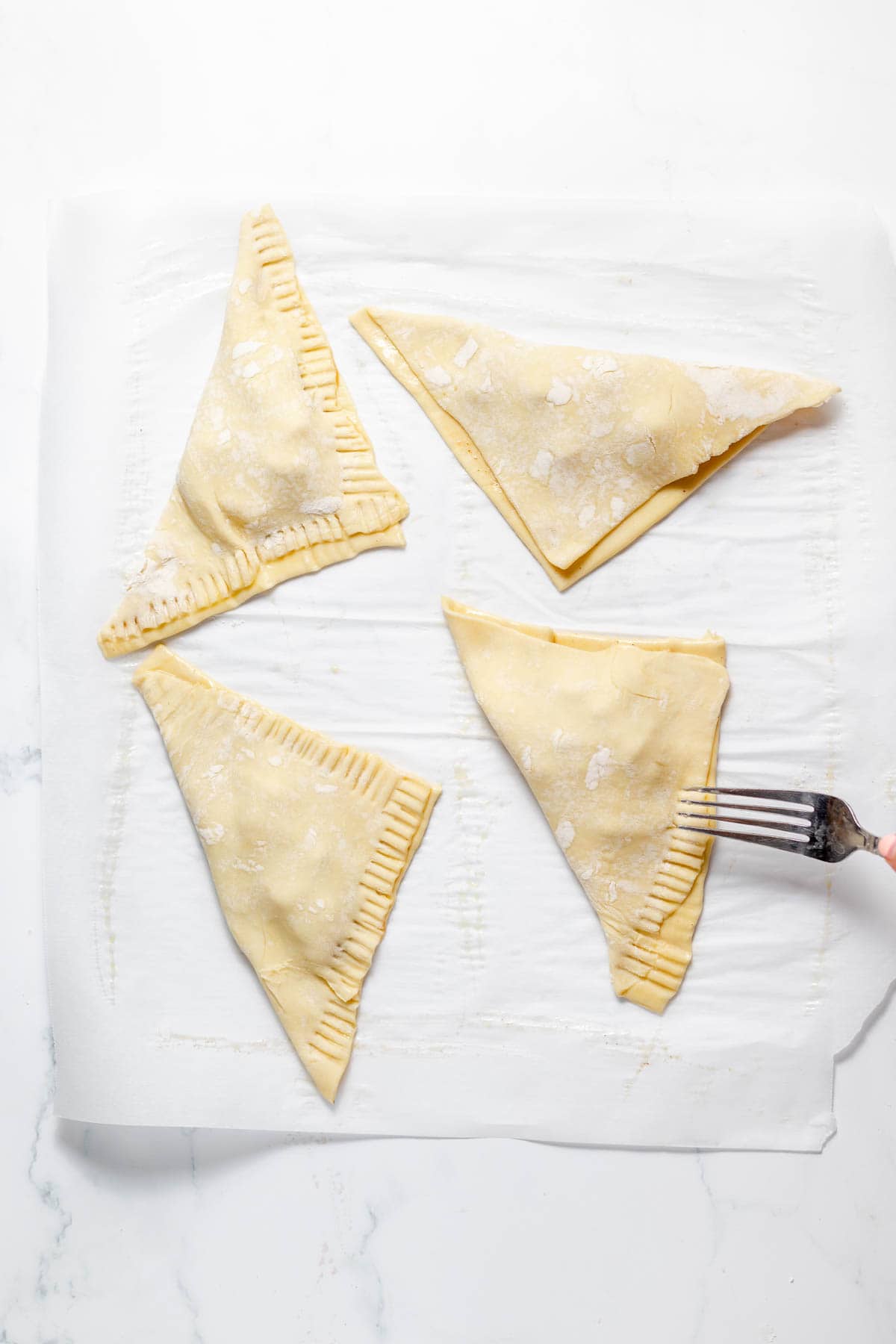 Crimping the edges of peach turnovers with a fork.