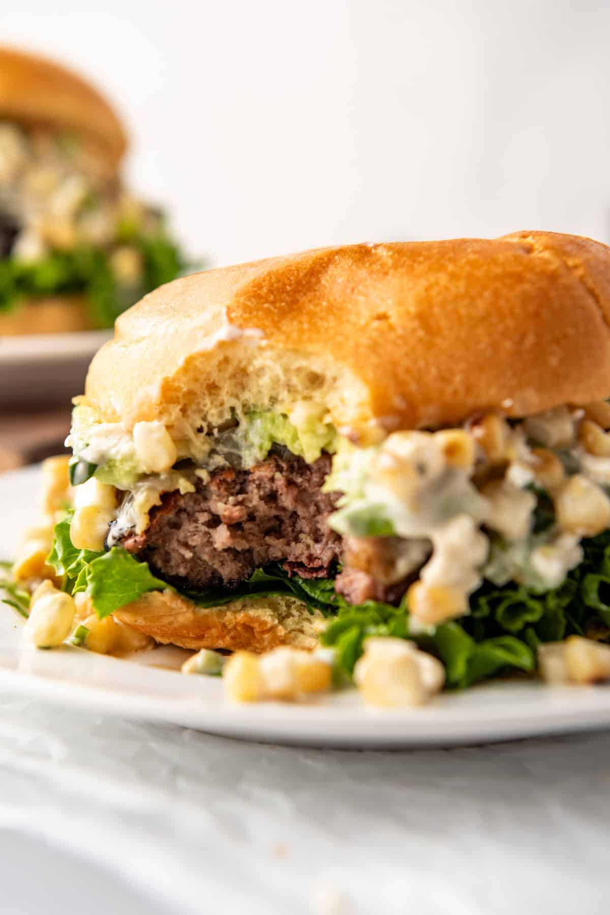 A Mexican street corn burger with a bite taken out of it.