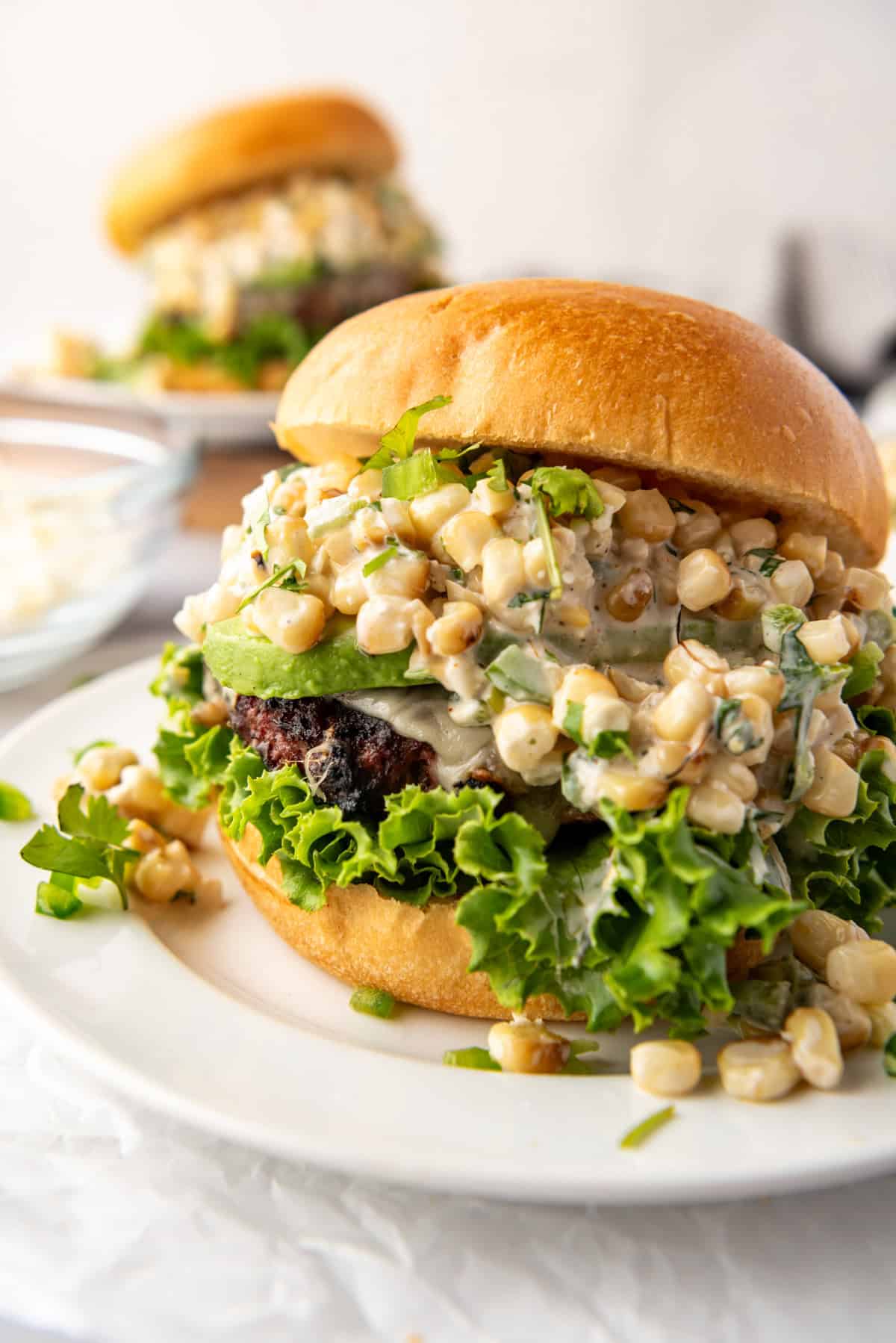 A close image of a cheeseburger topped with Mexican street corn topping.