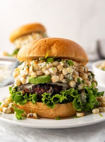 An image of an elote burger on a white plate.