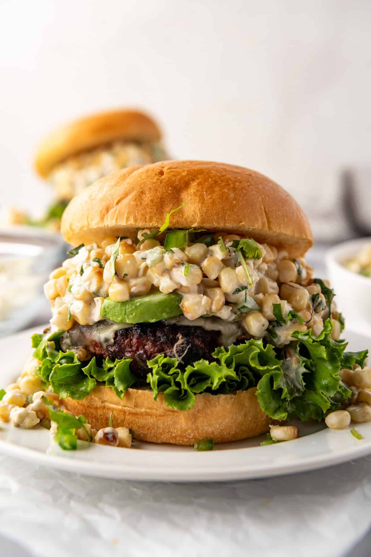 An image of an elote burger on a white plate.