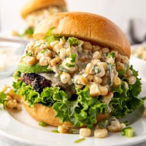 An image of an elote burger on a white plate.