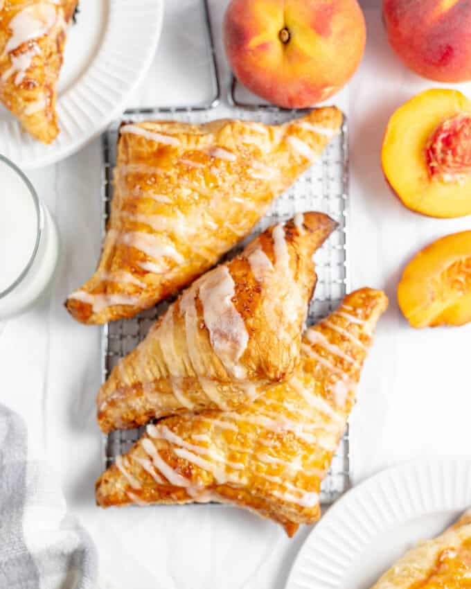 An overhead image of peach turnovers next to fresh peaches.