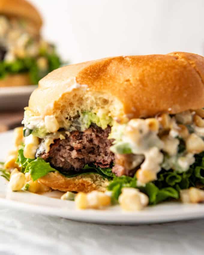 A Mexican street corn burger with a bite taken out of it.