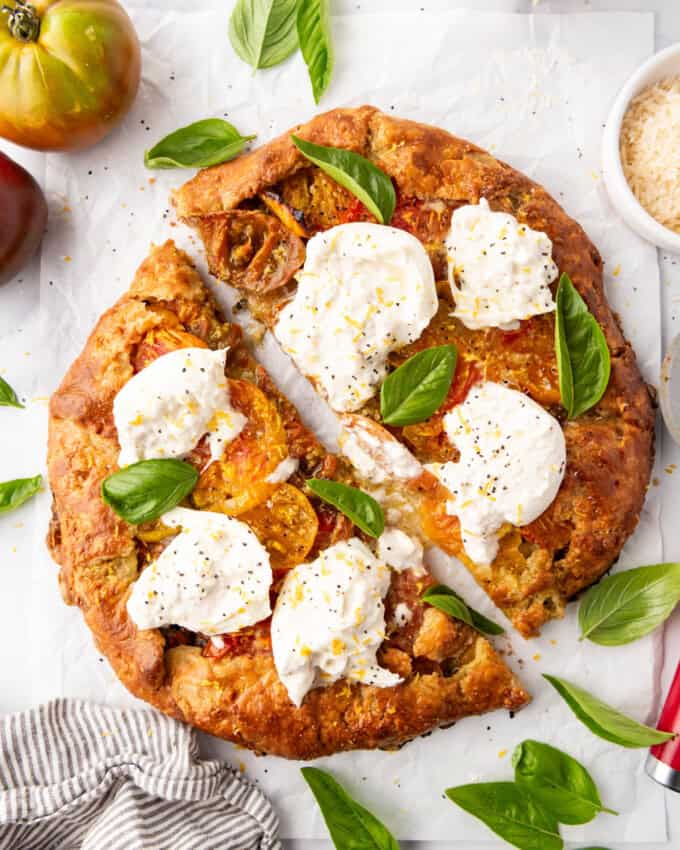 An overhead image of an heirloom tomato galette that has been sliced in half.