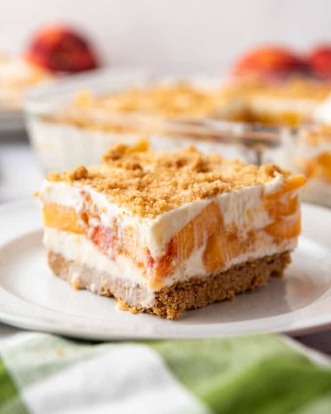 A slice of peaches and cream dessert on a white plate.