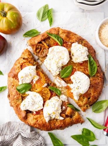 An overhead image of an heirloom tomato galette that has been sliced in half.