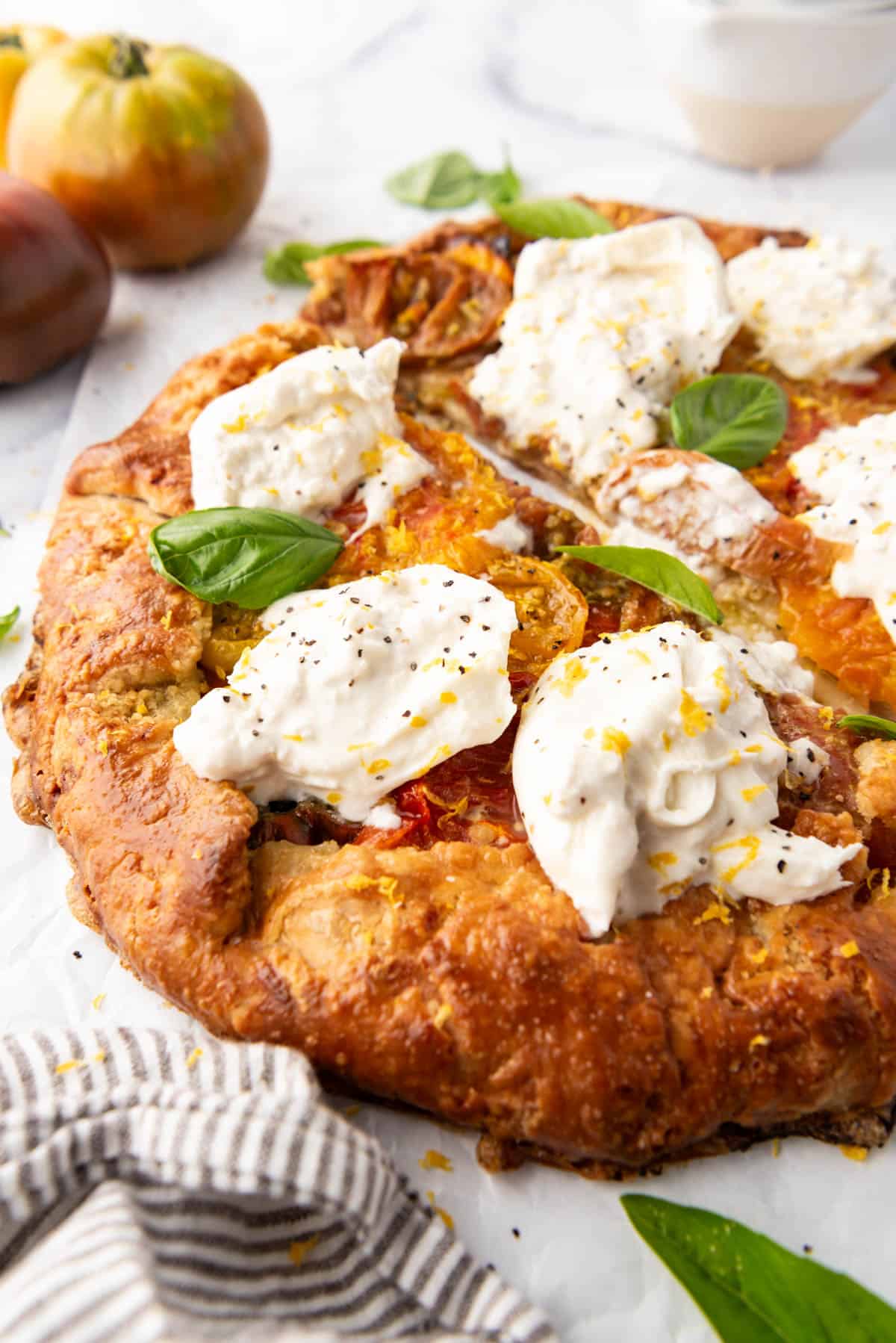 A side view of burrata cheese on top of an heirloom tomato galette.