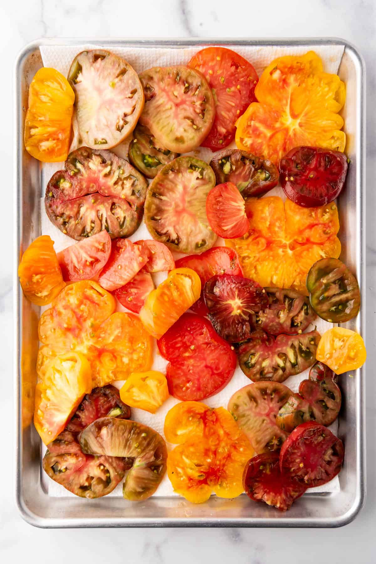 Sliced heirloom tomatoes on paper towels to drain juices.