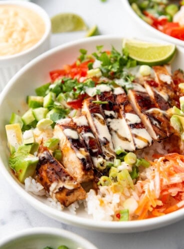 A close image of sliced huli huli chicken in a rice bowl.