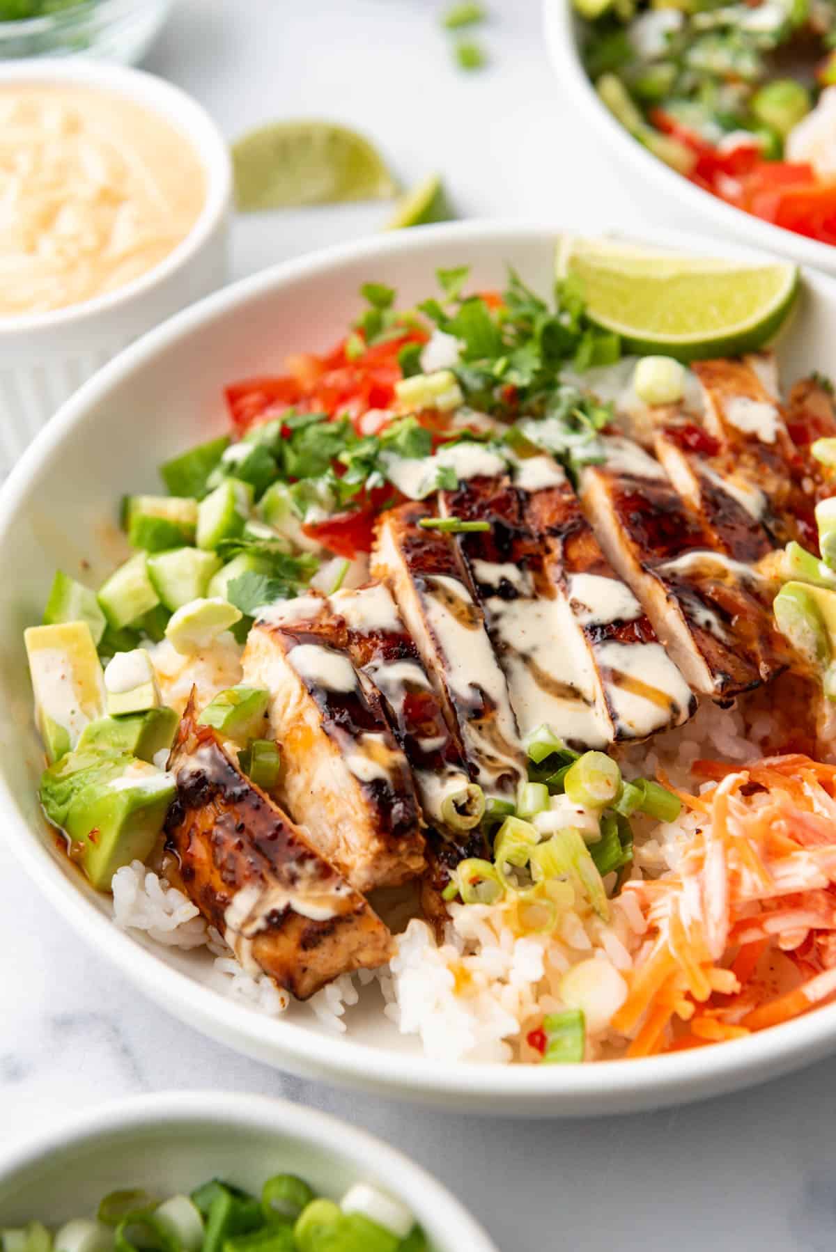 A close image of sliced huli huli chicken in a rice bowl.