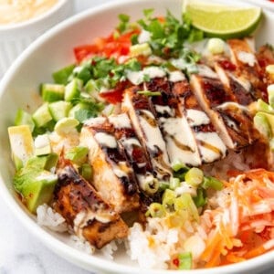 A close image of sliced huli huli chicken in a rice bowl.