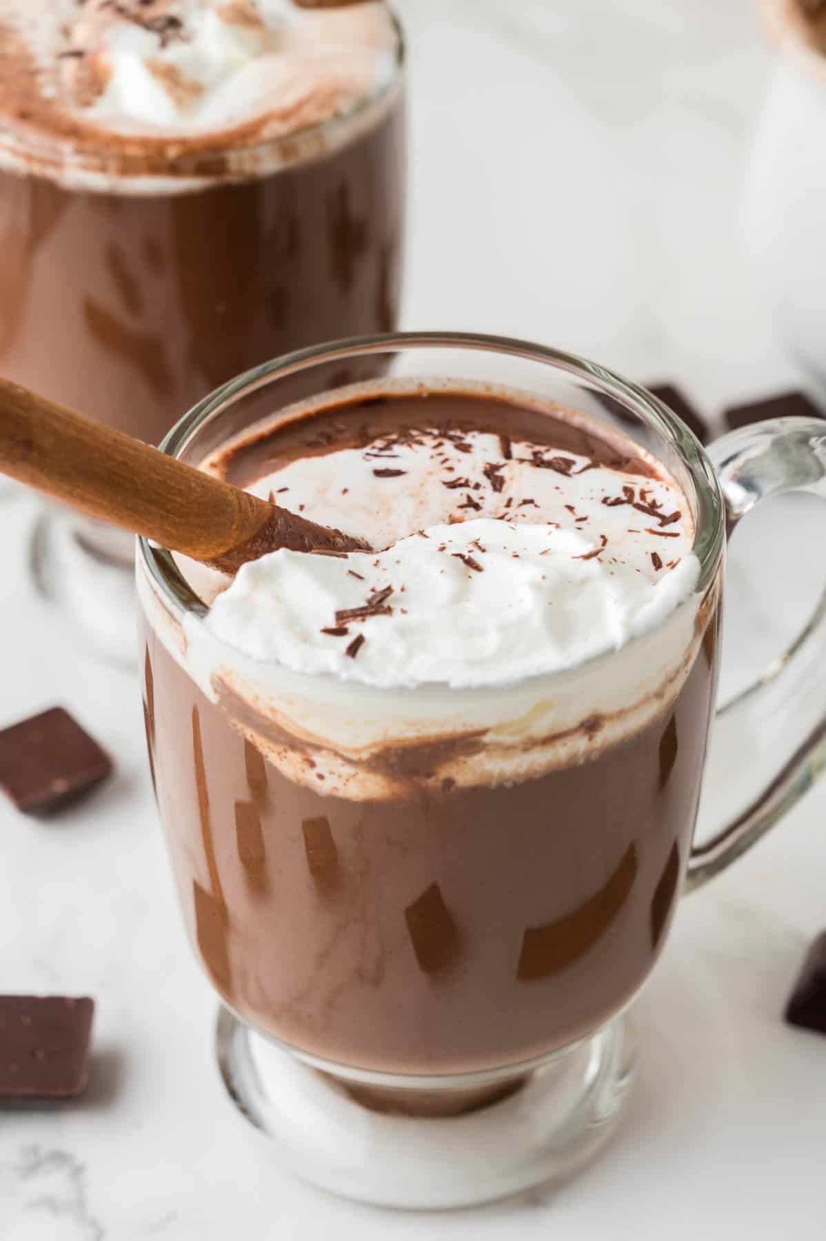 A glass mug of Mexican hot chocolate with cinnamon and whipped cream.